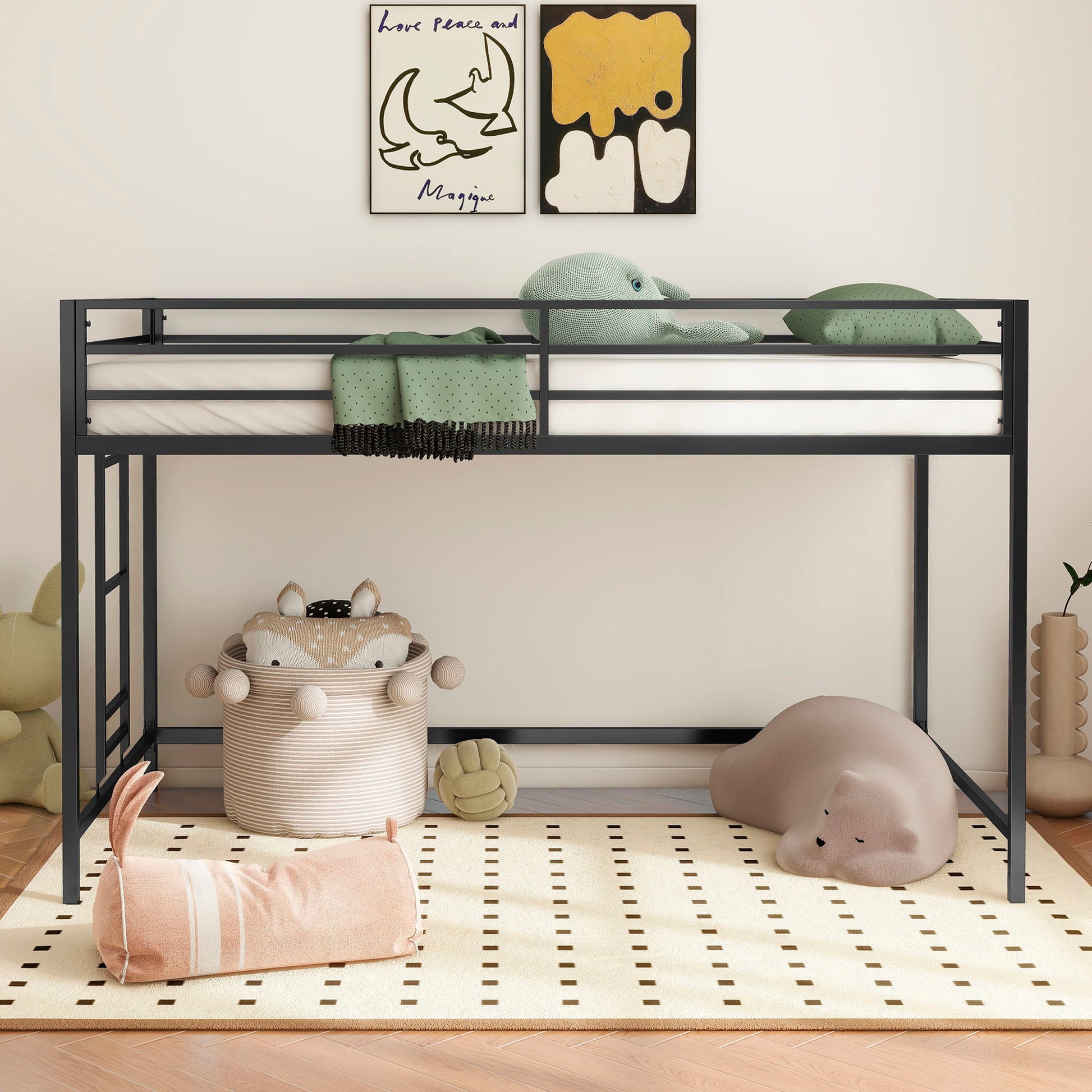 A child's room with the Adam - Junior Twin Loft Bunk in black, green stuffed animals on top, wall art, a round basket with animal ears, plush toy animals, and a cream rug with black dots on a wooden floor.