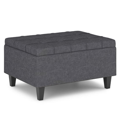 The Harrison Upholstered Coffee Table Storage Ottoman features a rectangular, dark gray design with a tufted top and short black legs, displayed against a white background.
