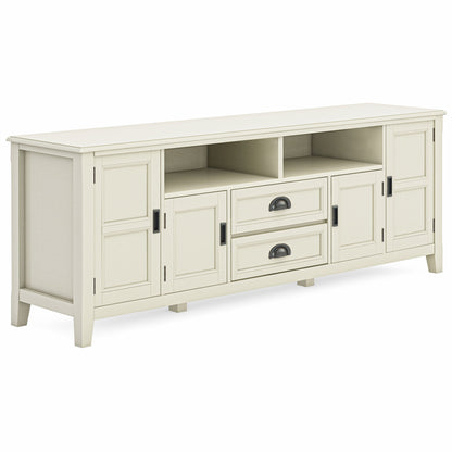 The Burlington TV Media Stand is a white wooden piece featuring two central drawers, two open shelves above, and four paneled cabinet doors with dark metal handles on each side.