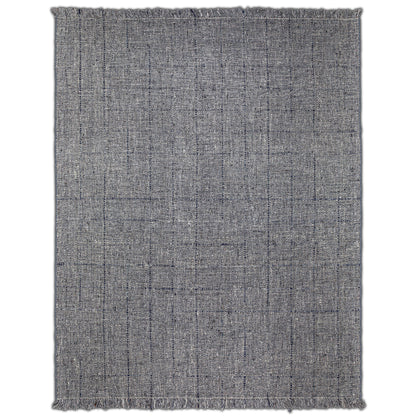 The Tenney Handcrafted Area Rug is rectangular and textured in gray, featuring subtle black lines in a loose grid pattern and short fringe on the edges.