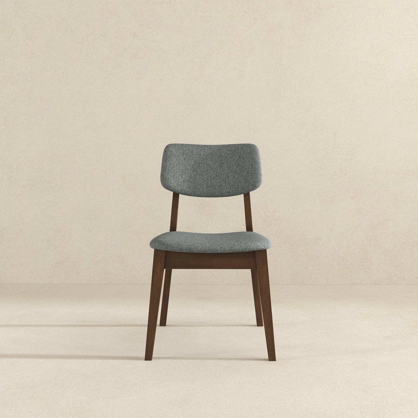 The Carlos Solid Back Side Chair (Set of 2) features a cushioned gray fabric seat and backrest with dark wooden legs and frame, shown against a plain beige background.