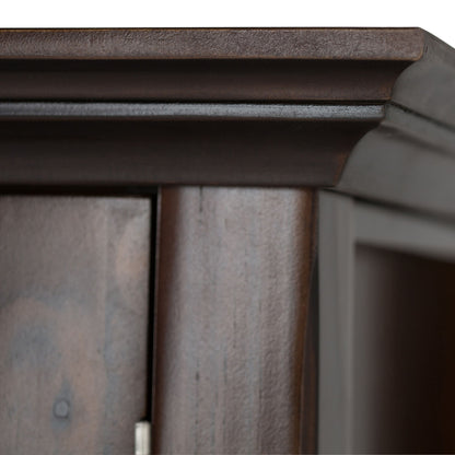 Close-up of the top corner of the Acadian Entryway Storage Cabinet in Brunette Brown, showcasing its smooth finish, raised decorative molding, and part of a door with visible hinge.