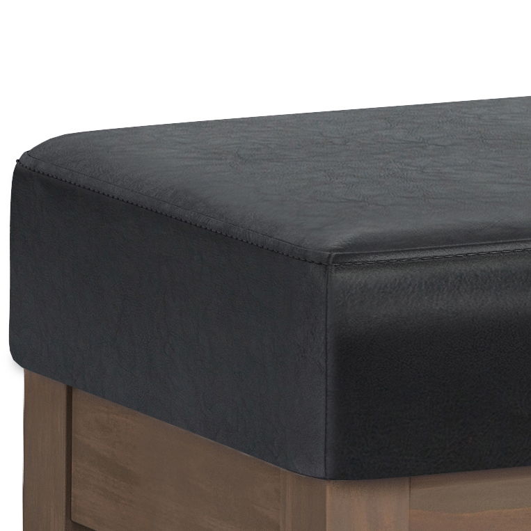 Close-up of the Milltown - Upholstered Ottoman Bench, featuring a black cushioned seat and wooden base, highlighting the corner where both materials meet.