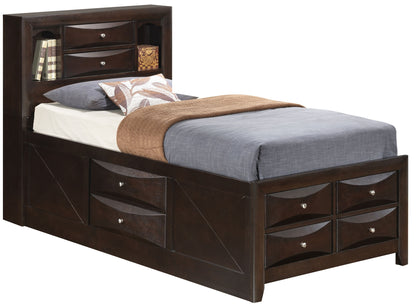 The Marilla Storage Bed With Bookcase Headboard is a dark wood twin bed featuring built-in drawers on the side and footboard, plus a headboard with shelves holding books and decor. It's shown made up with gray and brown bedding and a white pillow.