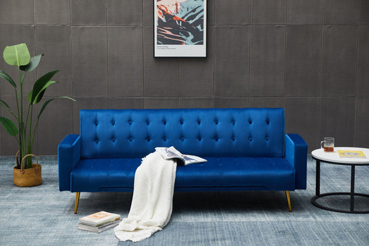 A modern living room features the Comfort Compact Design Sofa Bed in blue, topped with a white blanket, an open magazine, a potted plant nearby, a round side table with a drink, and wall art on a gray wall.