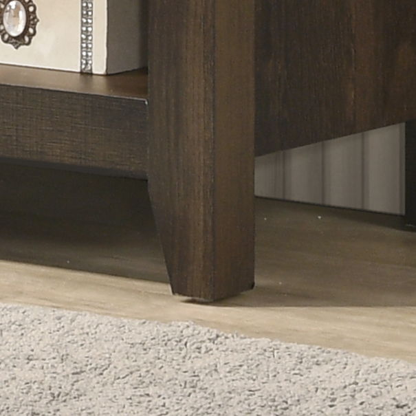 A close-up of the Benito TV Stand’s dark wooden leg on a wood floor, with a beige carpet nearby and a light-colored decorative box with jeweled knob placed on one of its open lower shelves.