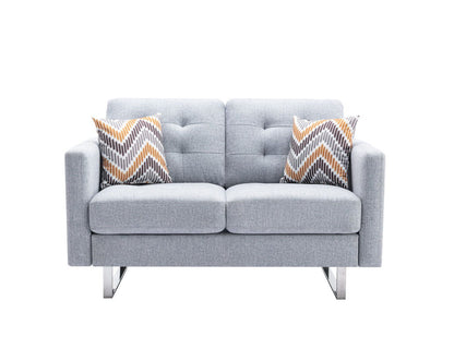 The Victoria loveseat features light gray linen fabric, a modern tufted back, square arms, metal legs, handy side pockets, and includes two chevron-patterned pillows in gray, white, and orange.