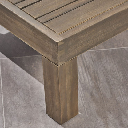 Close-up of the corner of the Alcove - L Shape Sofa Set, featuring a slatted wooden top and square legs, placed on a gray, stone-textured tiled floor.