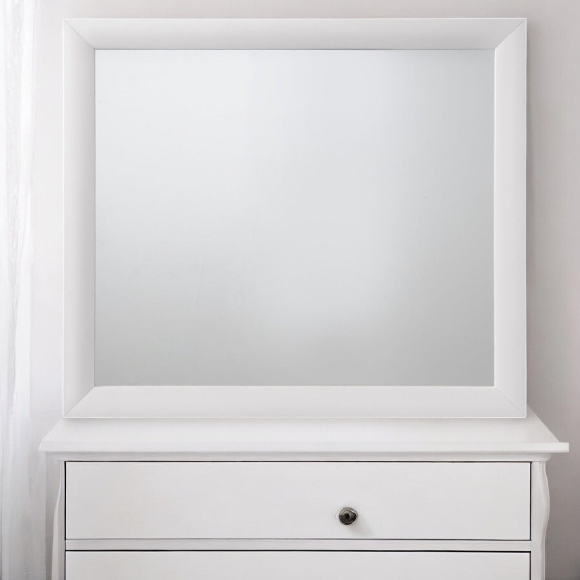 The Ireland - Contemporary Design Mirror, large and square with a white frame, is mounted above a white drawer unit featuring a single round metal knob against a plain light wall.