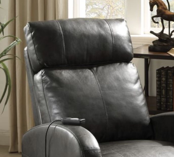 A close-up of the Ricardo Power Motion Recliner & Lift in brown, featuring a remote on the armrest next to a window with beige curtains and a decorative horse statue on a table in the background.