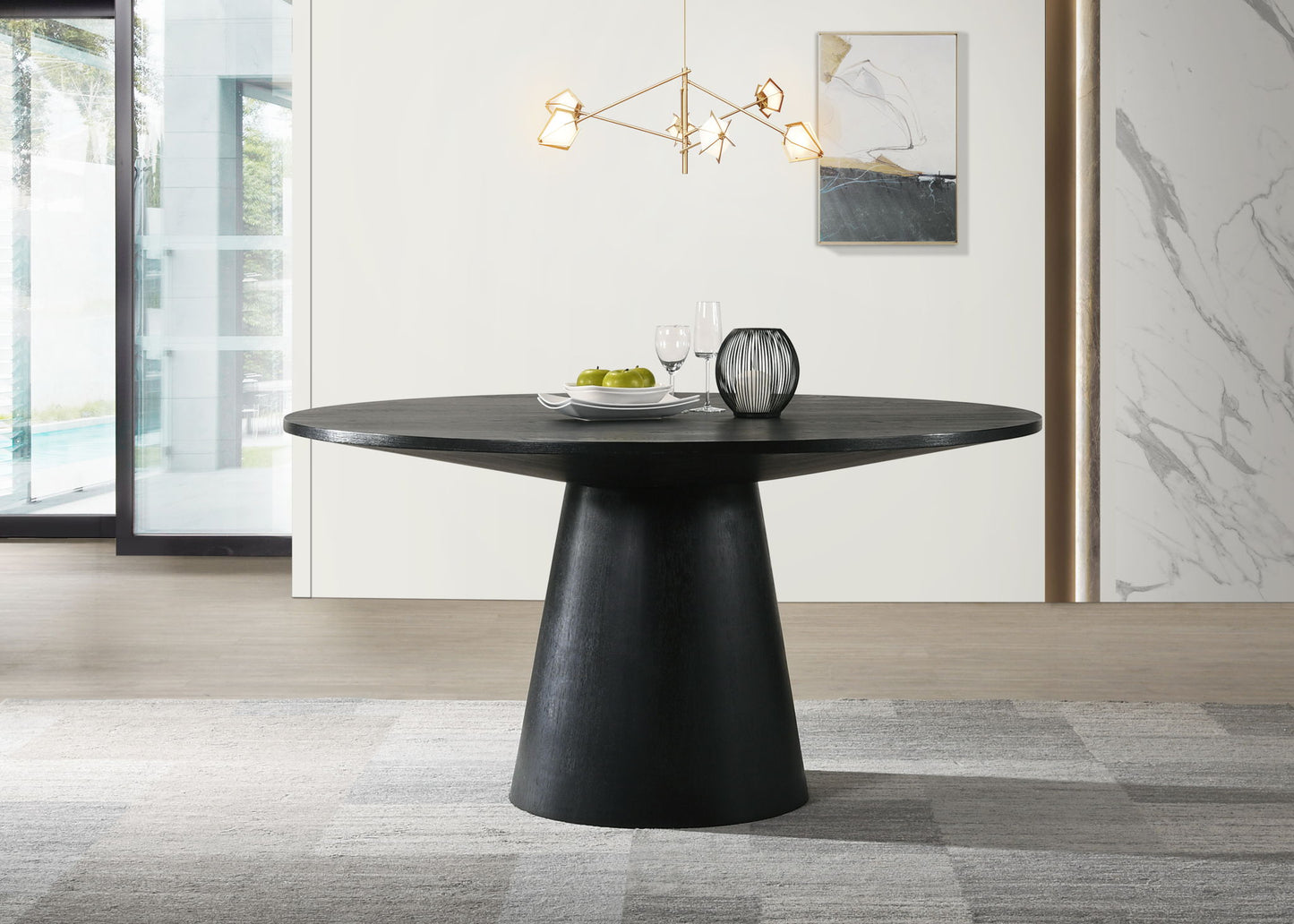 A modern dining area with the Jasper - Wide Contemporary Round Dining Table, set with two glasses, a plate of green apples, and a decorative vase. A geometric chandelier hangs above, with abstract art and a large window in the background.