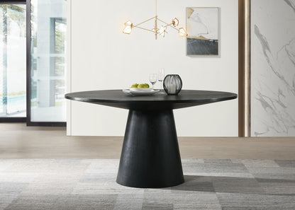 A modern dining area with the Jasper - Wide Contemporary Round Dining Table, set with two glasses, a plate of green apples, and a decorative vase. A geometric chandelier hangs above, with abstract art and a large window in the background.