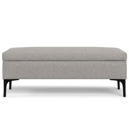 The Rebecca is a rectangular, multifunctional coffee table storage ottoman with light gray upholstery and four black, slightly angled legs, shown from the front against a white background.