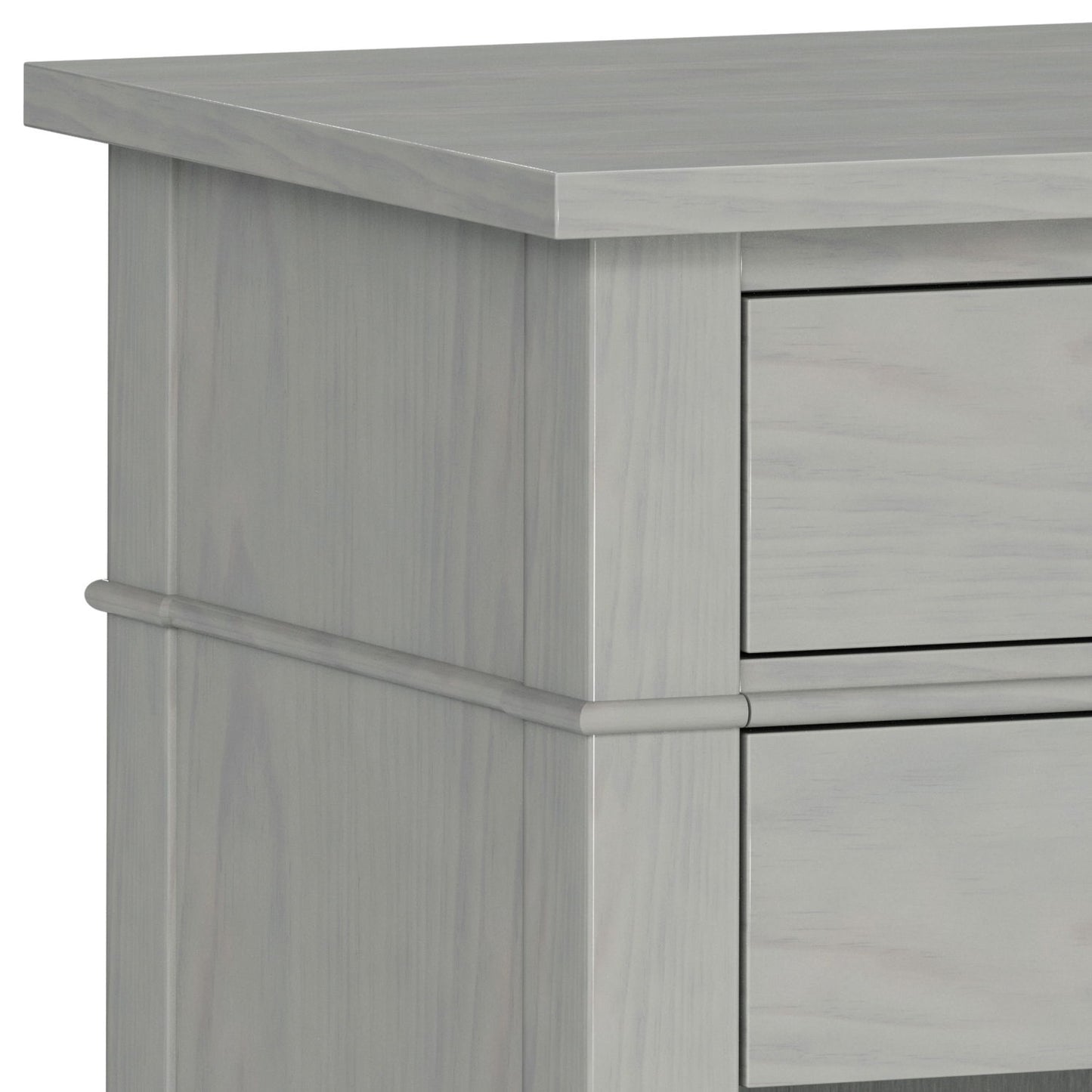 Close-up of the upper corner of the Carlton - Bedside Table, Handcrafted, in light gray wood, highlighting the smooth surface, clean lines, and part of two drawers.