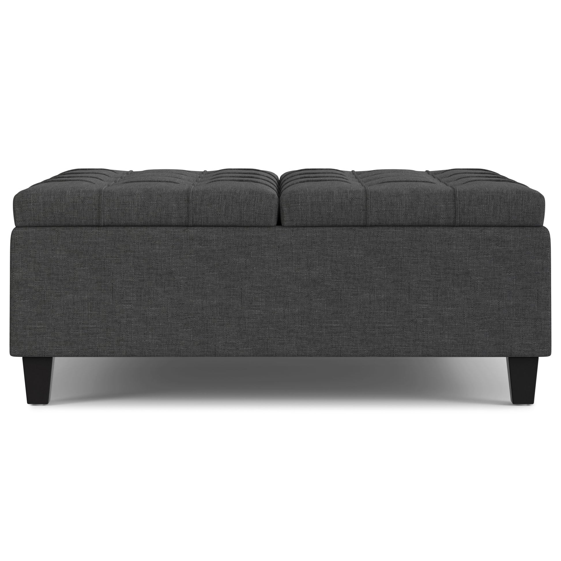 The Harrison Upholstered Coffee Table Storage Ottoman is rectangular, dark gray with tufted top cushioning, and features short black legs, shown from the front.
