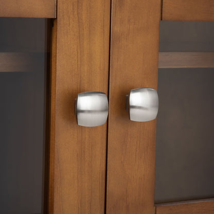 Close-up of two brushed metal, modern square knobs on the Acadian - Medium Storage Cabinet, Handcrafted. The cabinet features light brown wood and glass panel doors for a sleek, contemporary look.