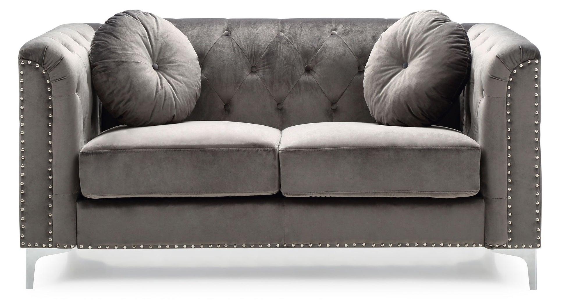 The Stylish Sloped Arm Loveseat features plush gray velvet upholstery, silver studs along the arms and base, a tufted backrest, and includes two round matching pillows.