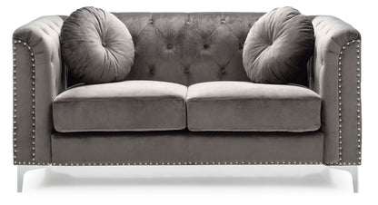 The Stylish Sloped Arm Loveseat features plush gray velvet upholstery, silver studs along the arms and base, a tufted backrest, and includes two round matching pillows.