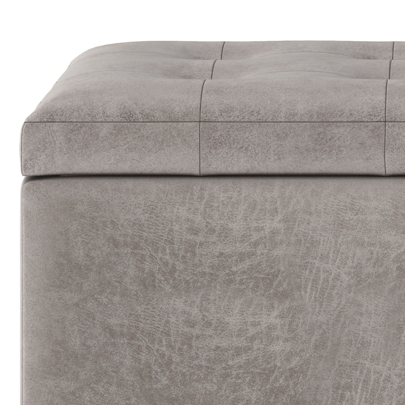 Close-up of the Cosmopolitan Upholstered Storage Ottoman featuring a gray, tufted, cushioned top and smooth textured sides.