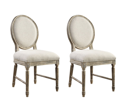 The Ludin Upholstered Dining Chairs (Set of 2) in brown feature round, cushioned backs and seats, weathered wood frames with carved accents, and tapered legs for a classic vintage look.