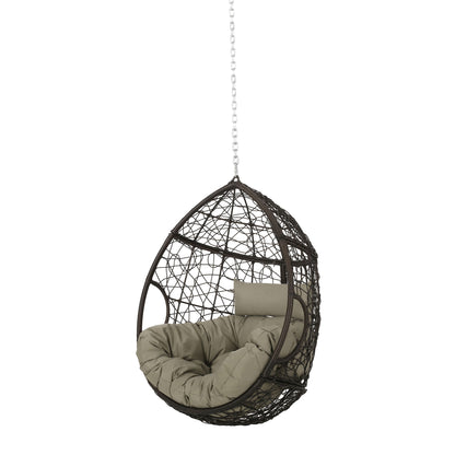 The Teardrop Hanging Chair features a woven dark brown design with a thick light beige cushion and pillow, suspended by an 8ft metal chain against a plain white background.