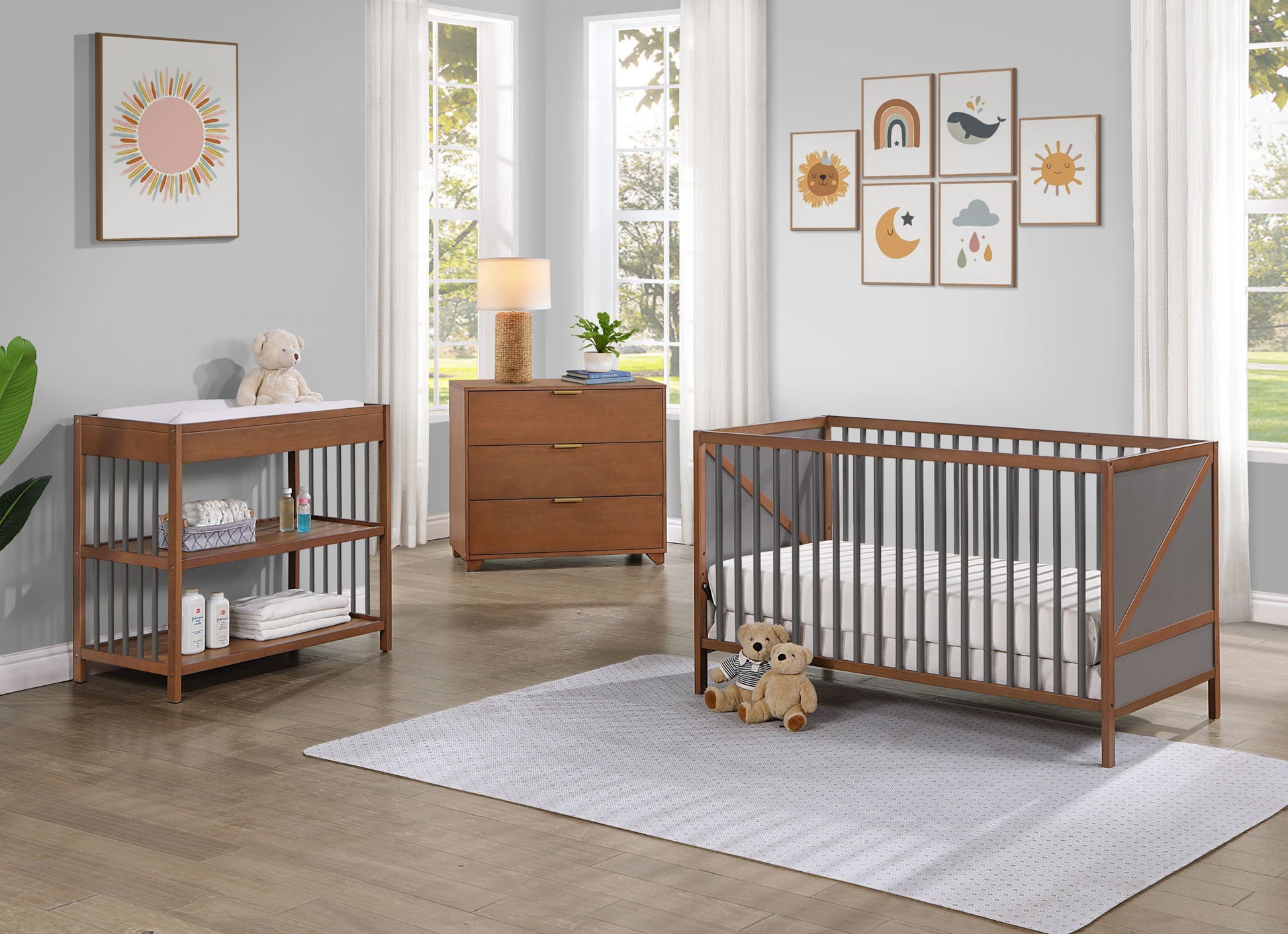 A modern nursery with the Pixie Zen 3-in-1 Crib in Walnut, a matching changing table with shelves, dresser, plush toys, wall art, lamp, and large windows with white curtains allowing natural light in.