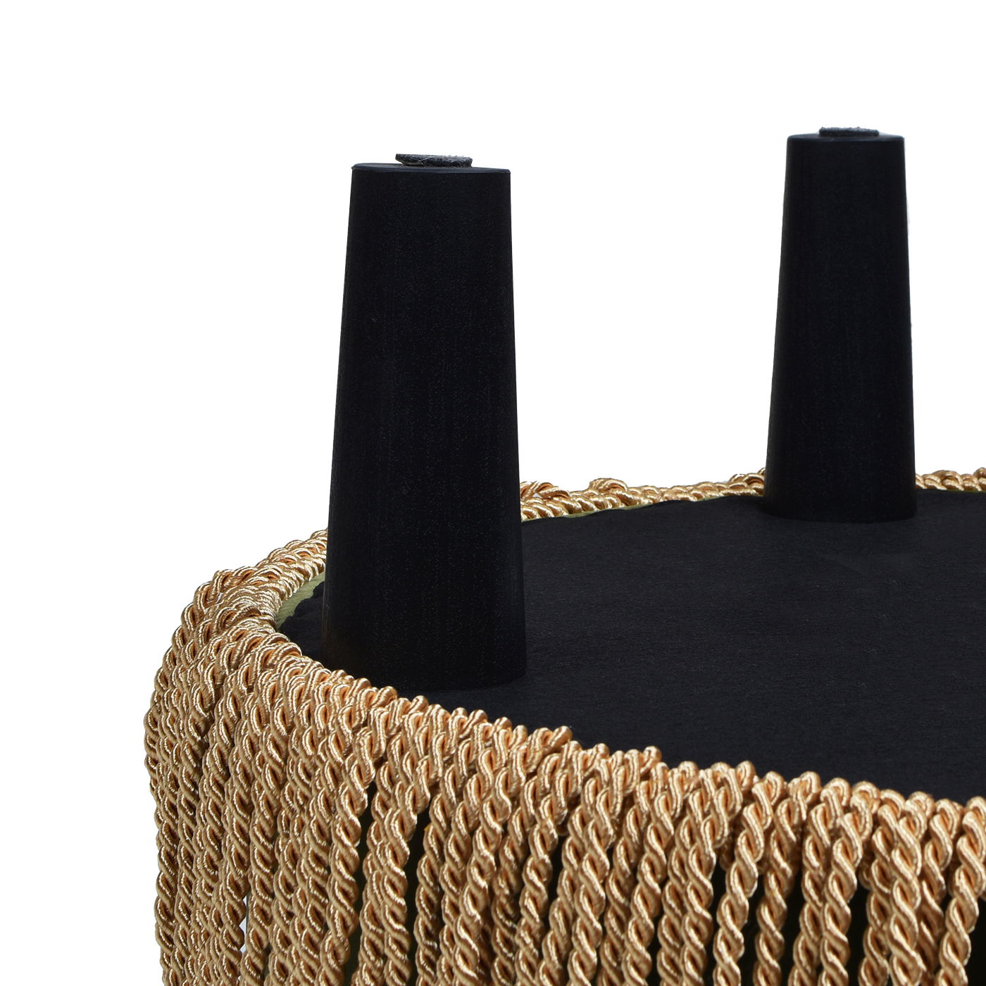 A close-up of the Yolanda Round Upholstered Accent Ottoman turned upside down, featuring two black angled legs and gold twisted rope fringe around the edge.