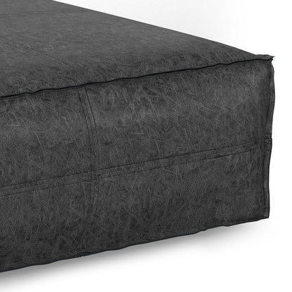 Close-up view of the corner of the Brody - Large Square, Coffee Table Pouf in dark gray, showing its textured fabric and visible edge stitching.
