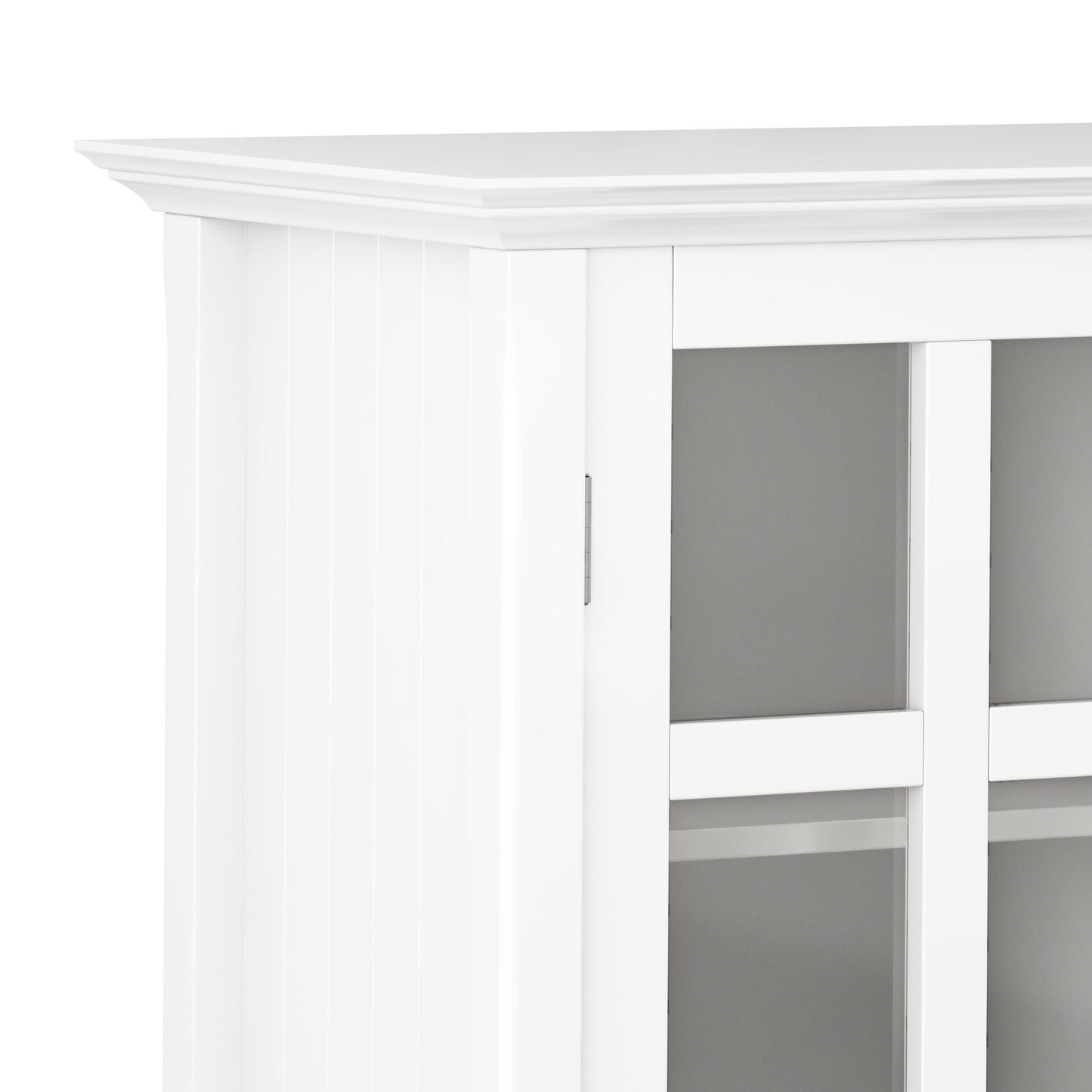 Close-up of the corner of the Acadian - Medium Storage Cabinet, Handcrafted. It features white wood, glass panel doors with decorative top trim, and shelves visible through the glass panels.