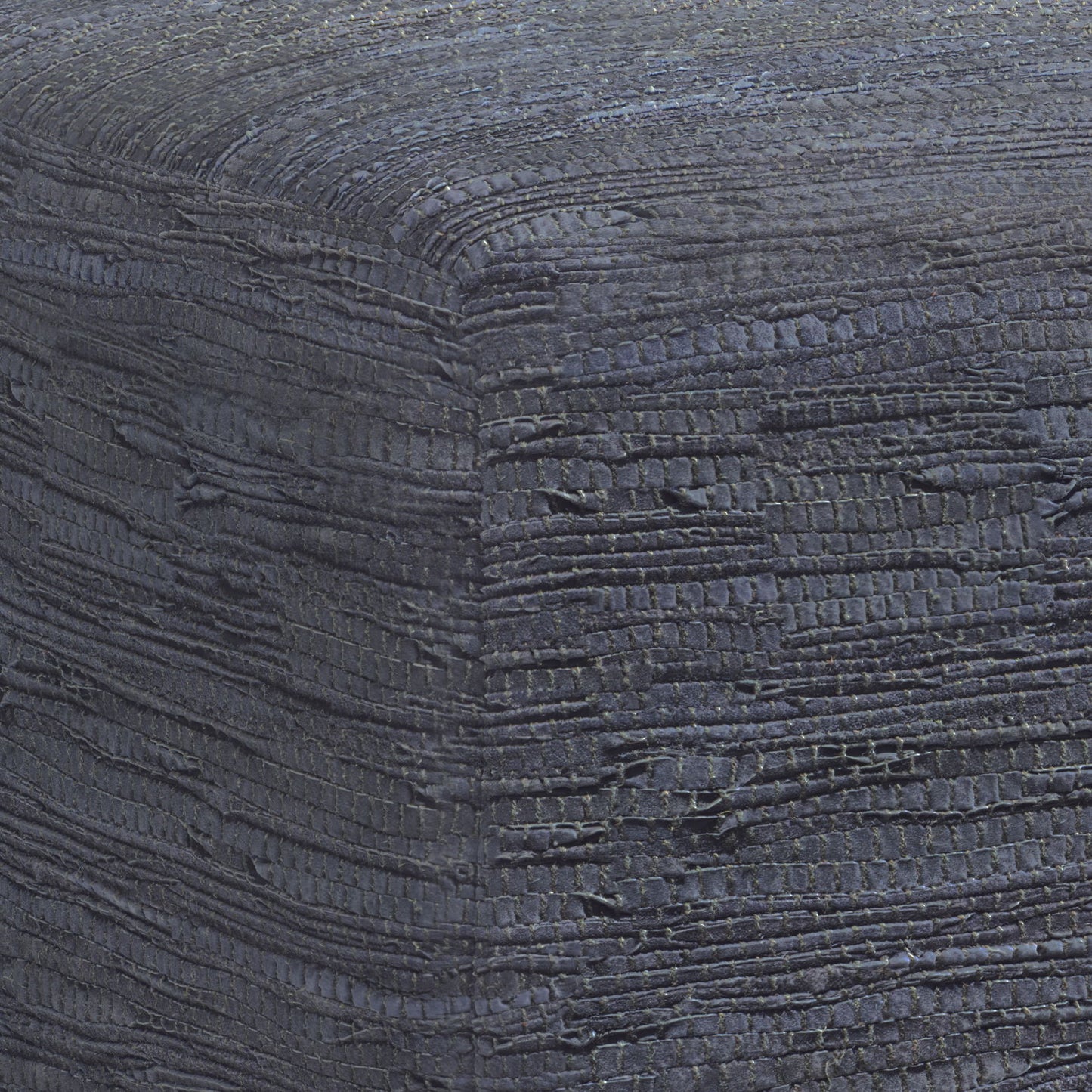 Close-up of the Fredrik - Handcrafted Square Pouf, highlighting its textured, dark fabric with woven horizontal and vertical patterns, subtle color variations, and raised details on the corner.
