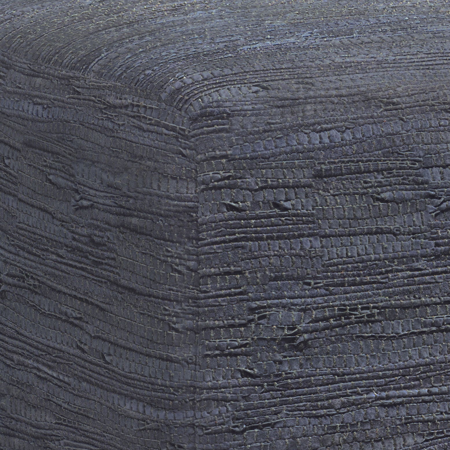 Close-up of the Fredrik - Handcrafted Square Pouf, highlighting its textured, dark fabric with woven horizontal and vertical patterns, subtle color variations, and raised details on the corner.