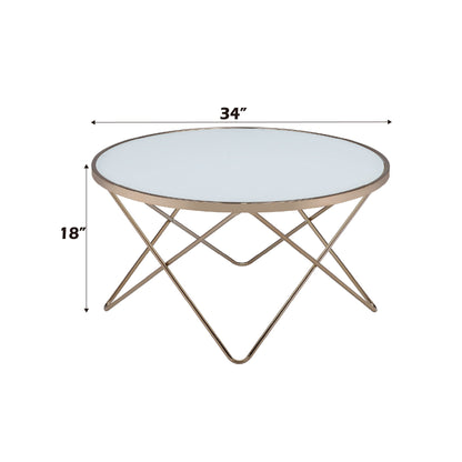 The Valora - Glass Coffee Table features a round glass top, gold metal frame, and crisscross legs. Dimensions: 34 inches wide x 18 inches high.