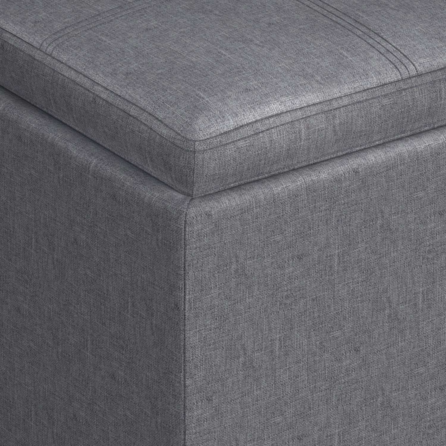 Close-up of the corner of the Rockwood Upholstered Cube Storage Ottoman With Tray, featuring gray textured fabric and visible stitching.