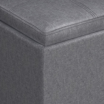 Close-up of the corner of the Rockwood Upholstered Cube Storage Ottoman With Tray, featuring gray textured fabric and visible stitching.