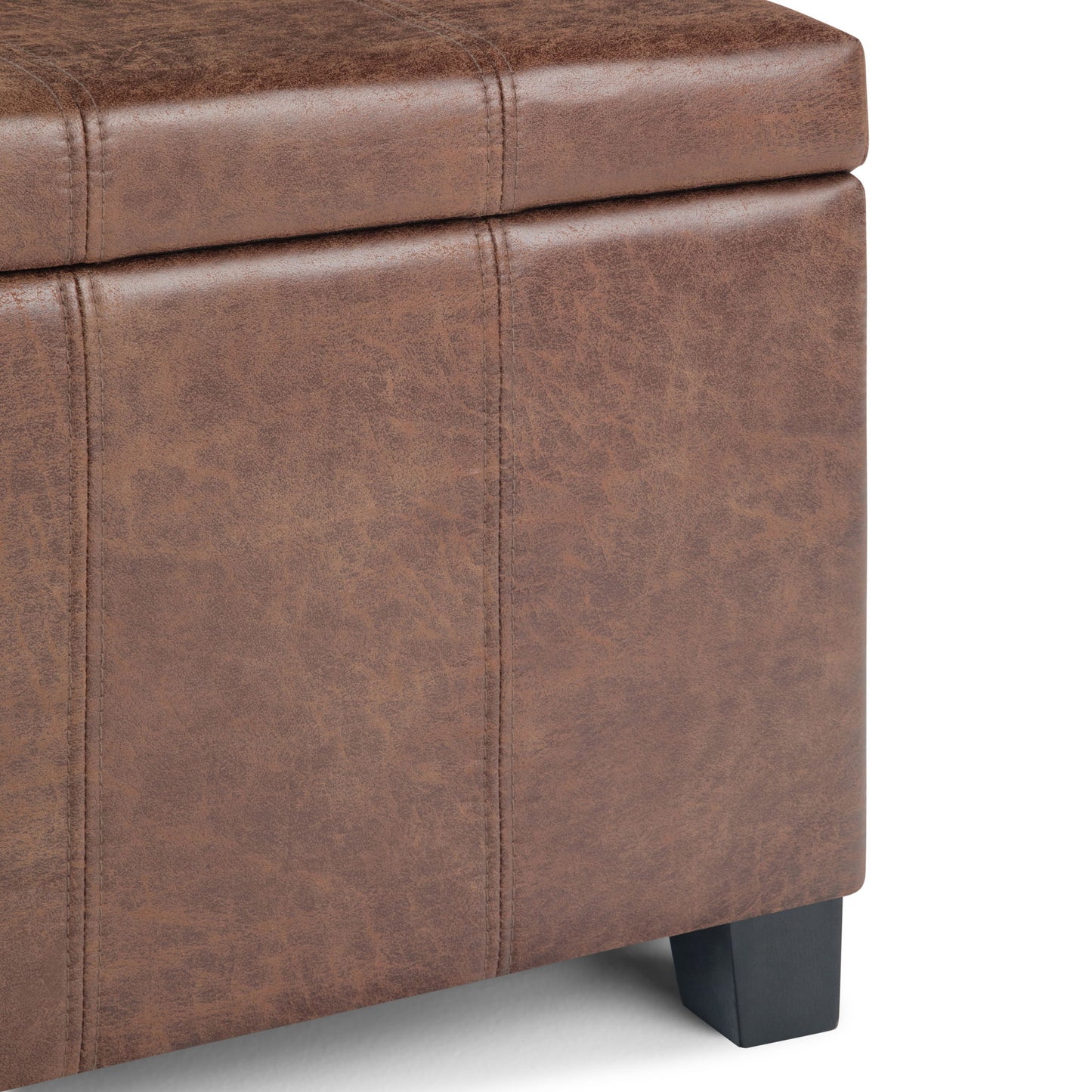 Close-up of the Dover Upholstered Storage Ottoman Bench in brown faux leather, featuring visible stitching, dark wood legs, and a slightly raised cushioned lid.