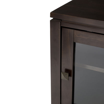 Close-up of the top corner of the Cosmopolitan - Handcrafted Medium Storage Cabinet, featuring a dark wood finish, glass door, small square metal handle, clean straight lines, and a smooth surface.