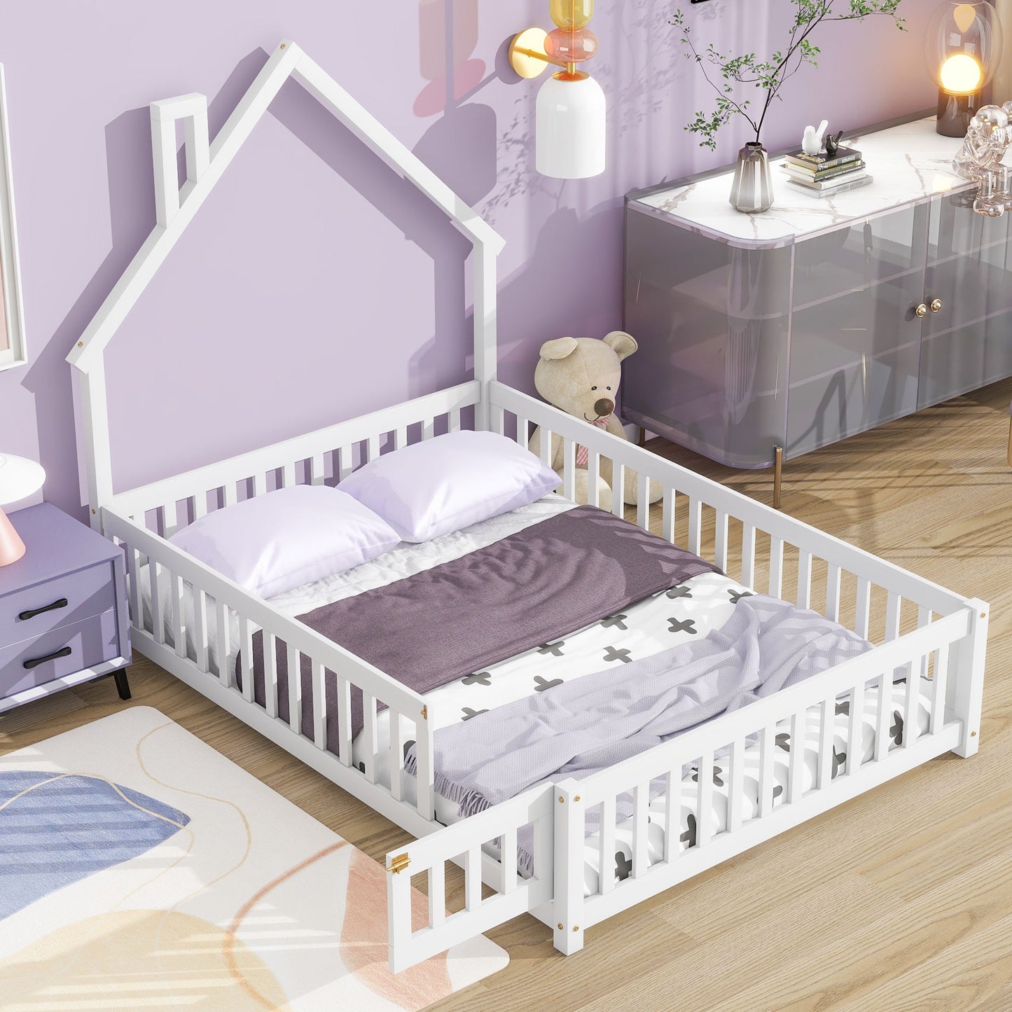 The House-Shaped Headboard Floor Bed With Fence, featuring safety rails and a playful white design, stands in a cozy room with light purple walls, soft bedding, a plush teddy bear, and modern décor.