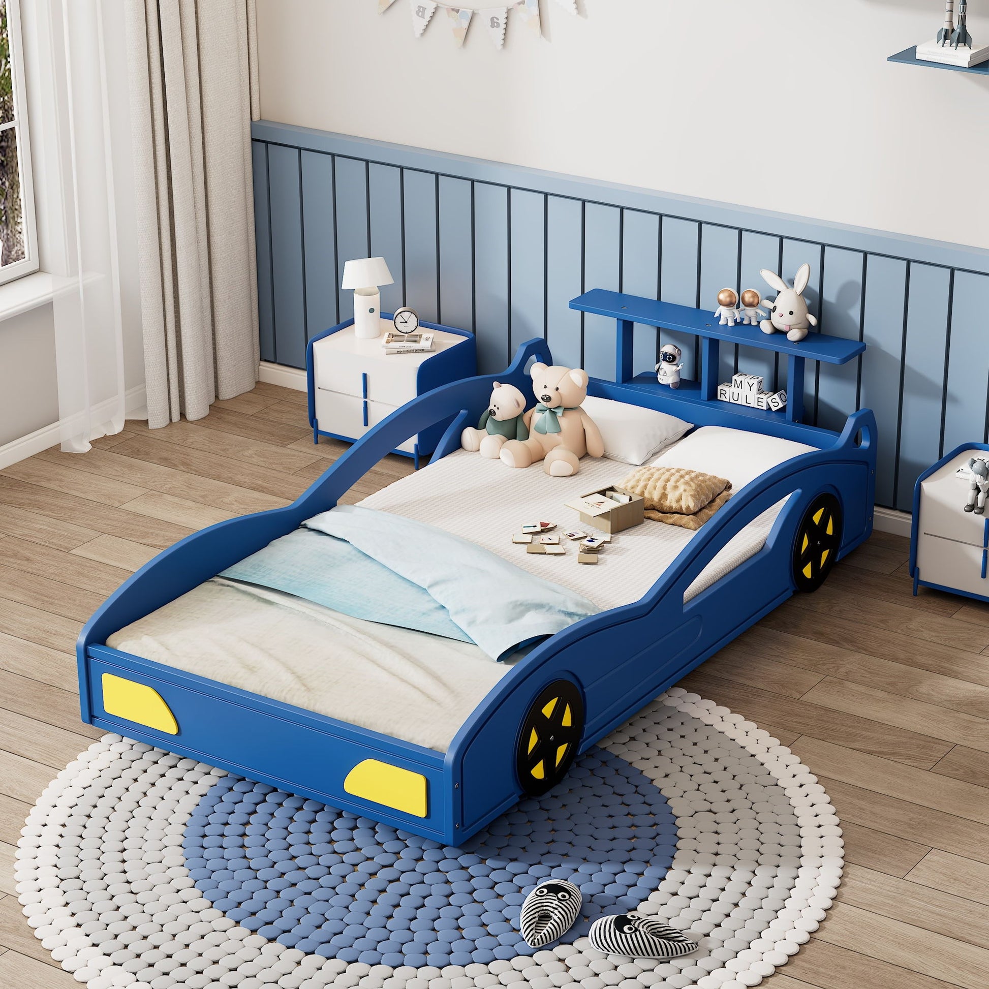 A Wooden Race Car Bed, Car Shaped Platform Twin Bed With Wheels For Teens, stands in a child’s room with blue walls, wood floors, a round rug, toys, bedding with stuffed animals, and a curtained window.