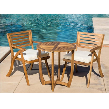 The Outdoor Dining Set With Coffee Table And 2 Chairs - Teak is arranged poolside, featuring two chairs with white cushions and a round table. Clear blue water provides a serene background for this elegant set.