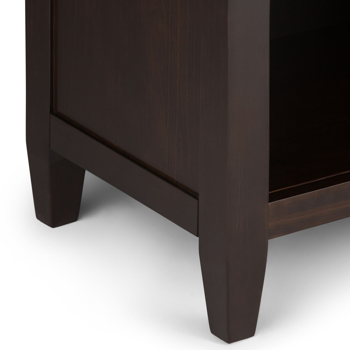 Close-up of the bottom corner of the Carlton - Bedside Table, Handcrafted, featuring two tapered legs and part of a lower shelf in dark wood against a white background.