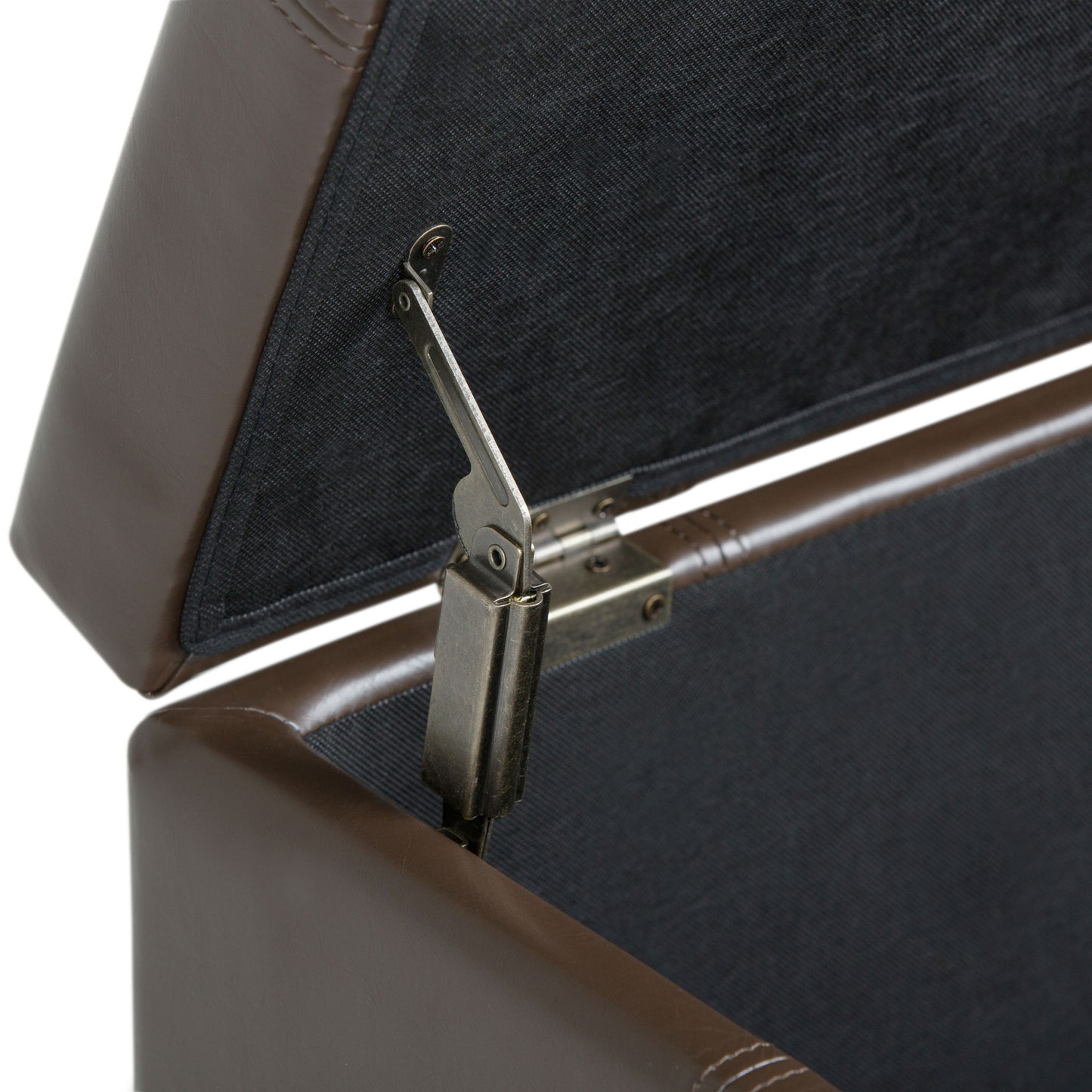 Close-up of the inside of the Dover - Upholstered Storage Ottoman Bench, featuring a sturdy metal hinge that keeps the lid open. The brown leather interior is lined with dark fabric for a refined look.