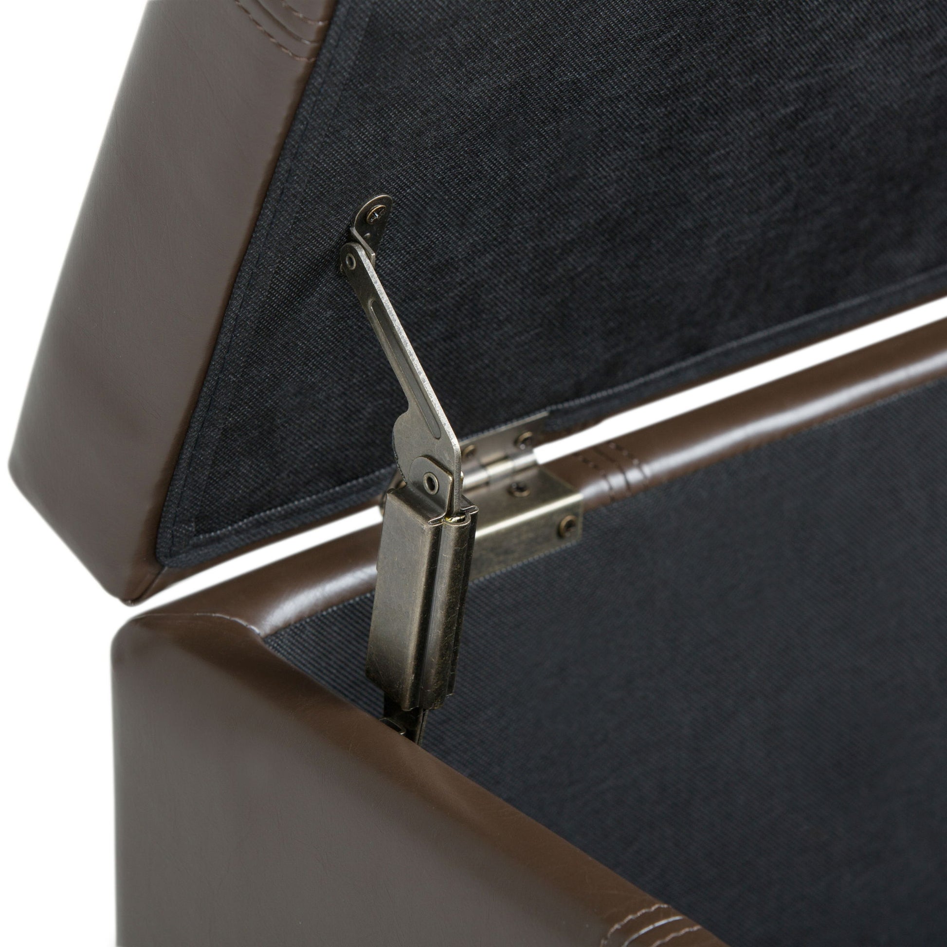 Close-up of the inside of the Dover - Upholstered Storage Ottoman Bench, featuring a sturdy metal hinge that keeps the lid open. The brown leather interior is lined with dark fabric for a refined look.