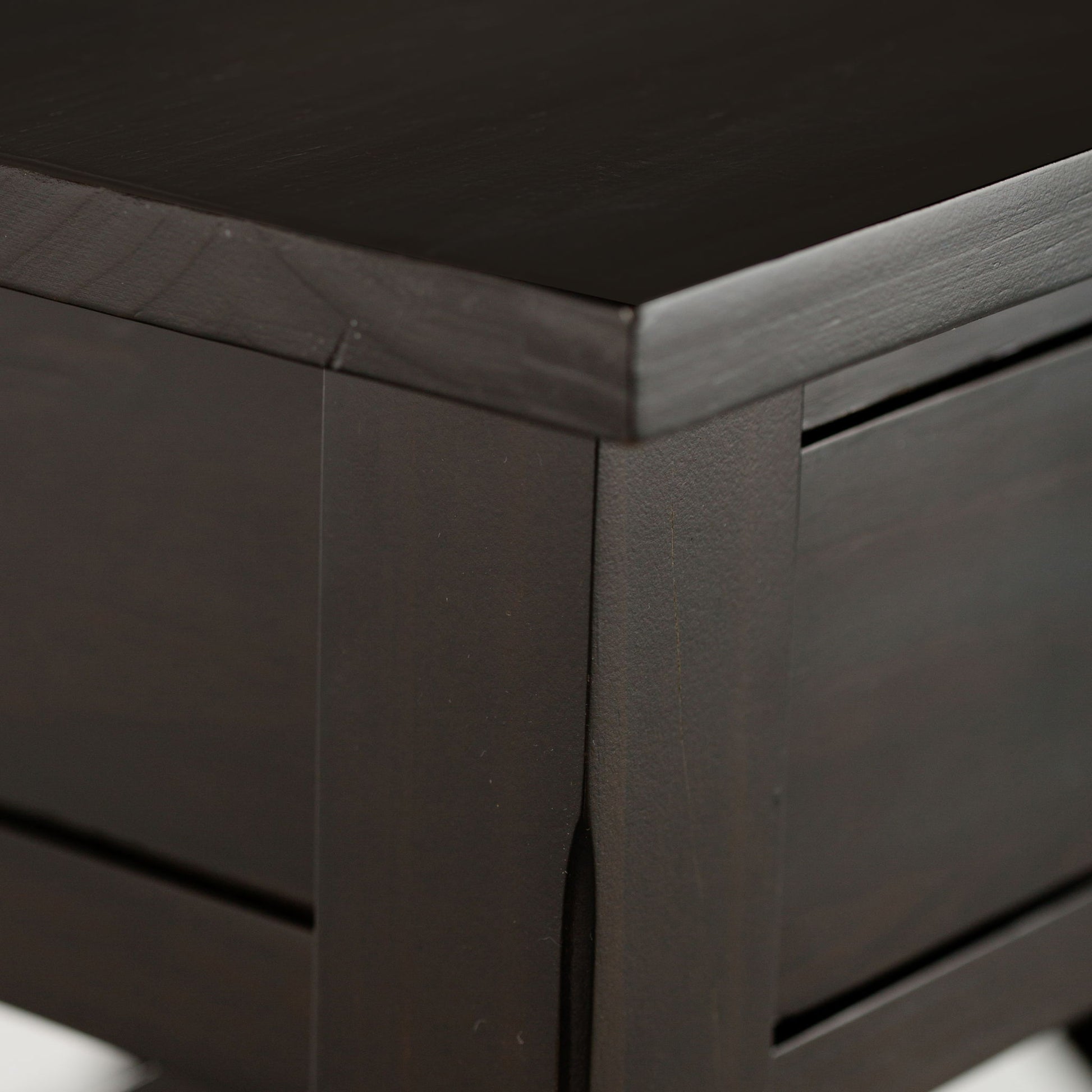 Close-up of the Kitchener - Handcrafted Table’s corner, highlighting its smooth, polished dark wood surface and clean, modern lines.