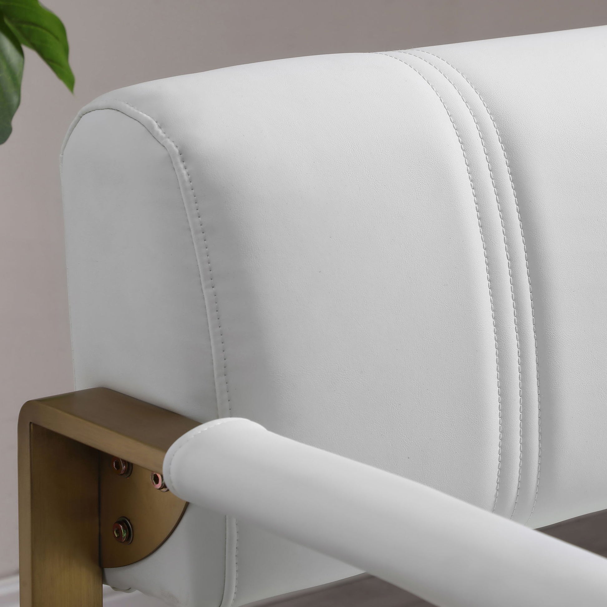 Close-up of the Modern Upholstery Accent Loveseat Sofa for Living Room, a 2-seater with golden metal arms and white upholstery. Double-stitched detailing enhances the backrest. A green plant appears partially in the top left corner.