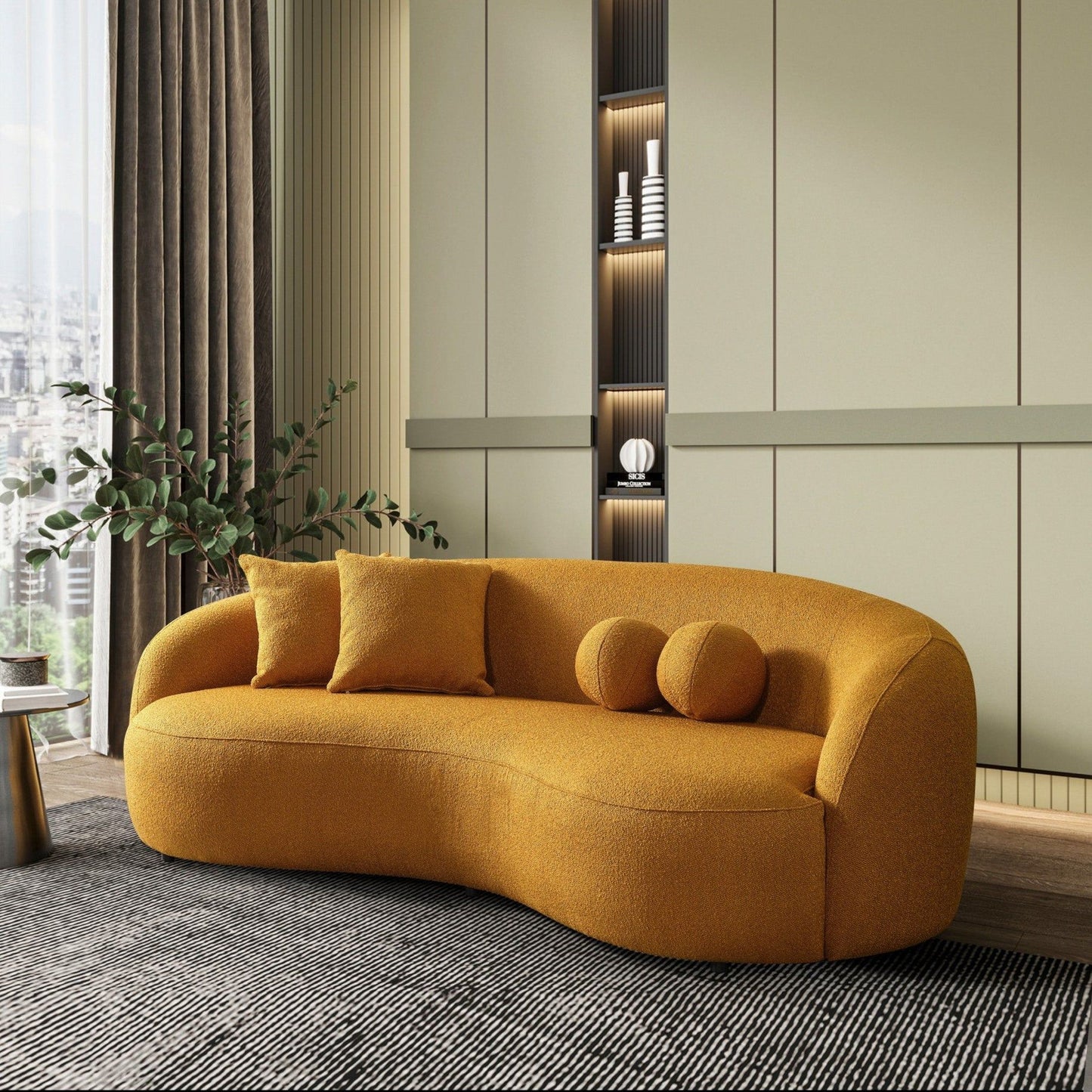 A modern living room showcases the Drake - Japandi Style Curvy Boucle Sofa in mustard yellow, three cushions, a large gray rug, leafy plant, and built-in shelves with décor against pale green paneled walls.
