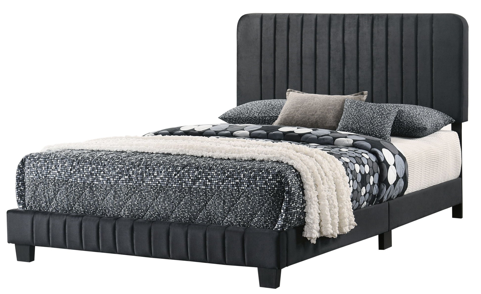The Lodi - Bed features a tall, upholstered black headboard with a matching frame and black legs. It is styled with black and white patterned bedding, coordinating pillows, and a textured cream throw blanket for a modern look.