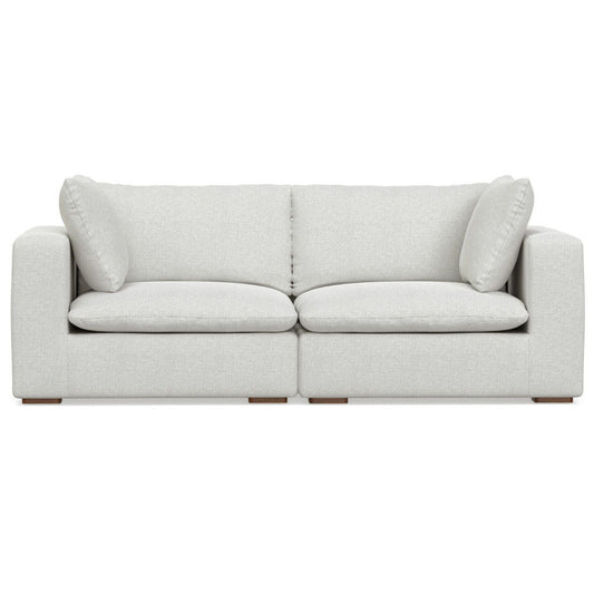 The Jasmine - Handcrafted Sofa is a modern light gray fabric piece with two large seat cushions, two back cushions, two matching side pillows, wide armrests, and a boxy design.