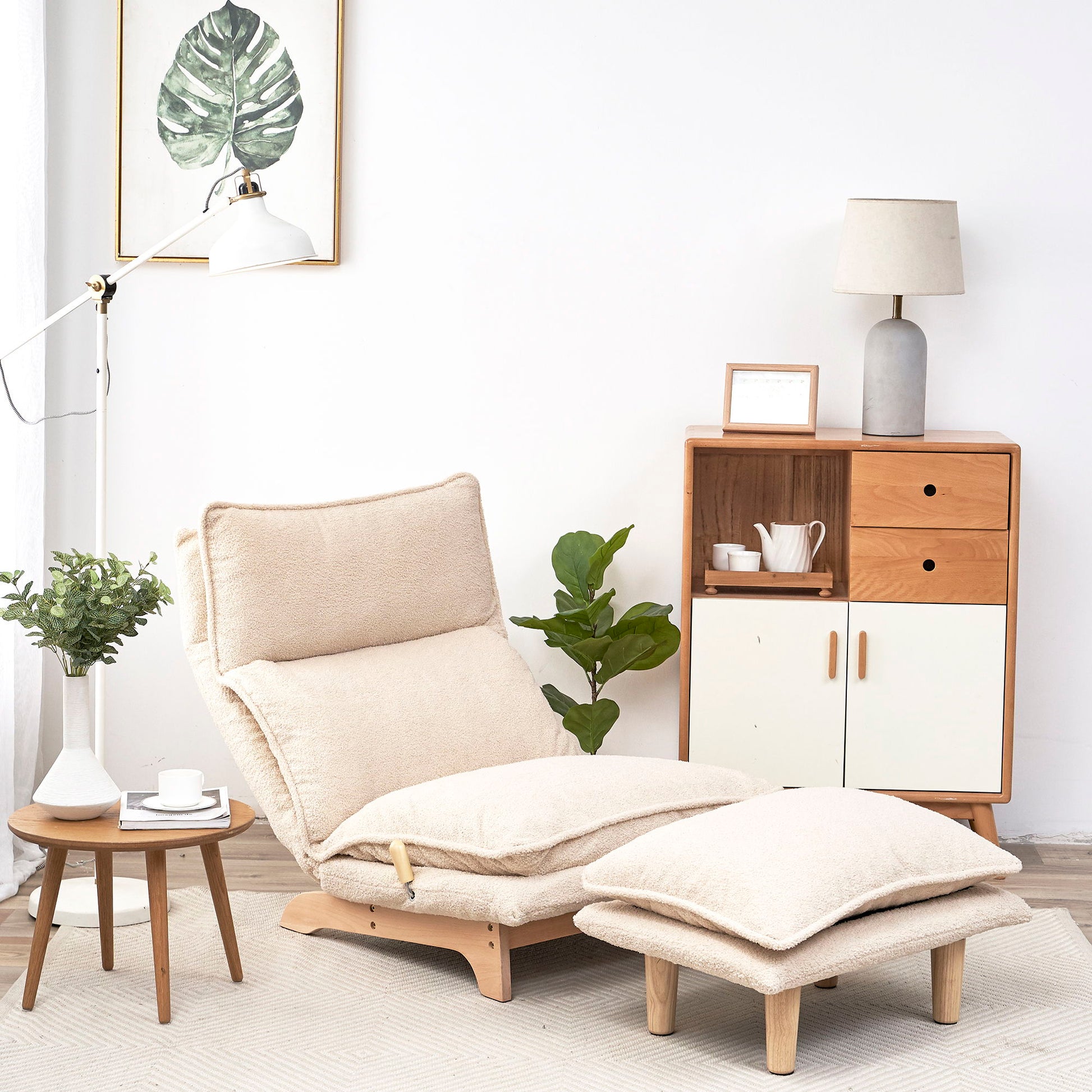 A cozy modern living room featuring a Single Lazy Sofa Chair Leisure Foldable Reclining Chair with matching ottoman, a small wooden side table with a plant and teacup, floor lamp, plant, and wooden cabinet against a white wall.
