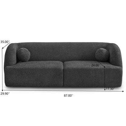 The Anna French Boucle Sofa features a dark gray, modern curved design with two round cushions. Dimensions: 87" wide, 35" tall, 29.9" deep, with a 24" seat depth and a 17.3" seat height.