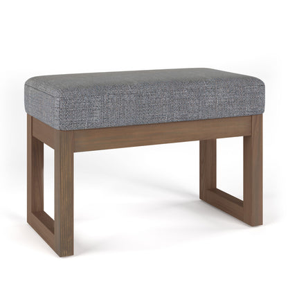The Milltown Upholstered Ottoman Bench features a cushioned gray fabric seat and a wooden base with clean, rectangular lines, shown against a plain white background.